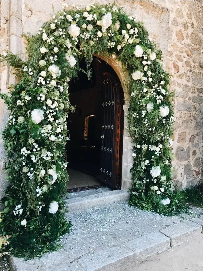 arco de flores blanco en entrada de iglesia