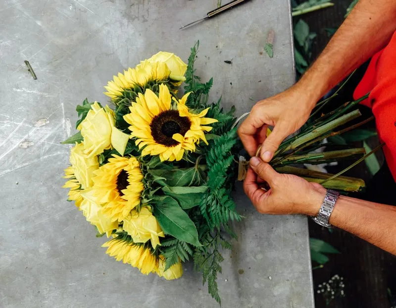 florista atando un ramo de girasoles con rosas