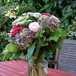 un ramo de hortensias y rosas en un jardin encima de una mesa