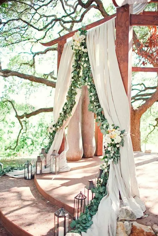 una decoracion de una boda campestre con una guirnalda de eucalipto y rosas