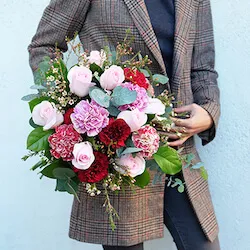 chica con chaqueta con un ramo de flores con rosas y claveles