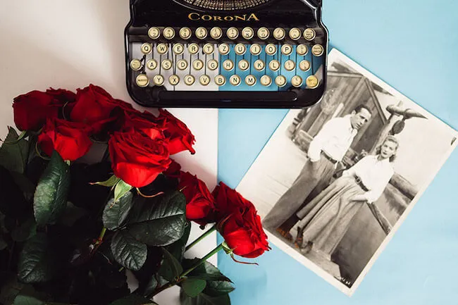 rosas rojas encima de una mesa con una maquina de escribir