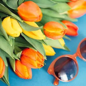 detalle de tulipanes naranjas y amarillos en una mesa azul