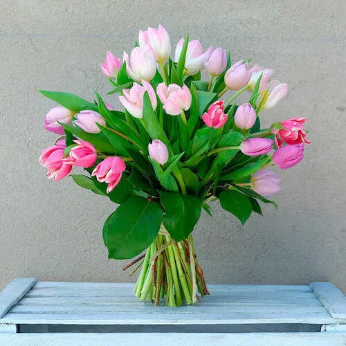 ramo de tulipanes rosa y lilas encima de una caja de madera