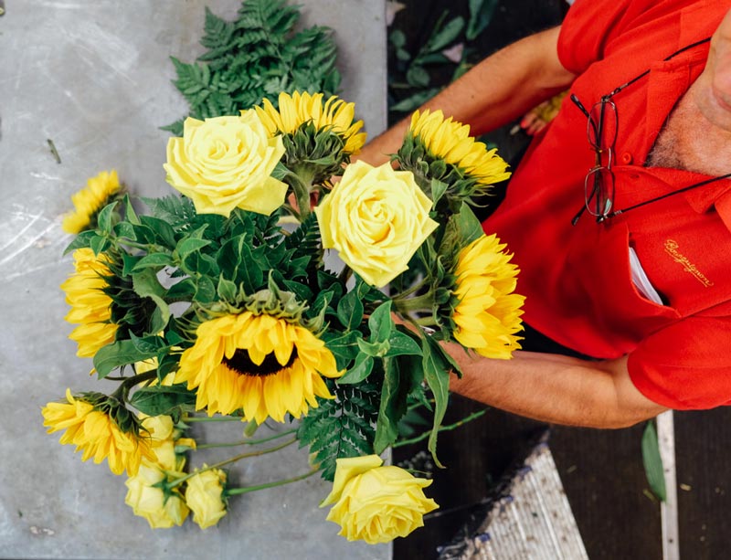 florista preparando un ramo de girasoles y rosas amarillas
