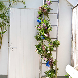 una guirnalda de hortensias y flores de verano atado a una escalera