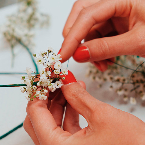 detalle de una florista atando paniculata para hacer una corona de pelo