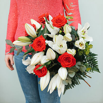 ramo de lirios blancos y rosas rojas sobre fondo azul 