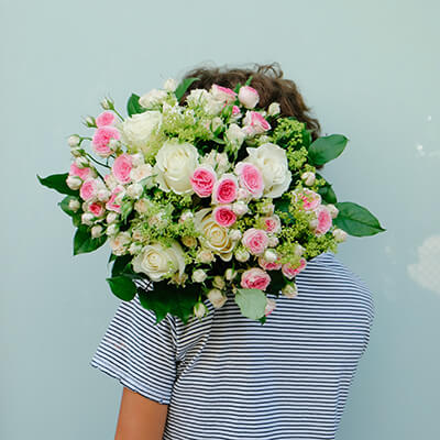 chica sujetando ramo de rosas mii edén sobre fondo azul 