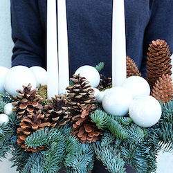 detalle de un centro de navidad con piñas y velas