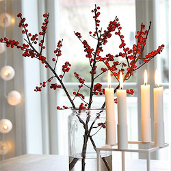 tallos de ilex rojo en con velas blancas