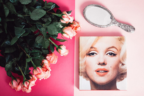 rosas de color rosa y naranja en una mesa rosa con espejo