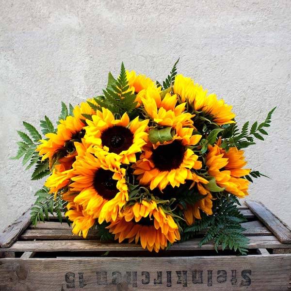ramo de girasoles amarillos encima de una caja de madera
