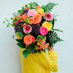 chica con un ramo de flores con rosas de diferentes colores y gerberas