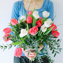 mujer con un ramo de tulipanes rosas y blancos con eucalipto