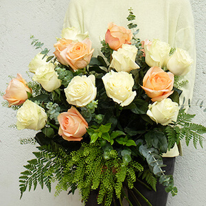 mujer con un ramo de rosas de color blanco y melocoton